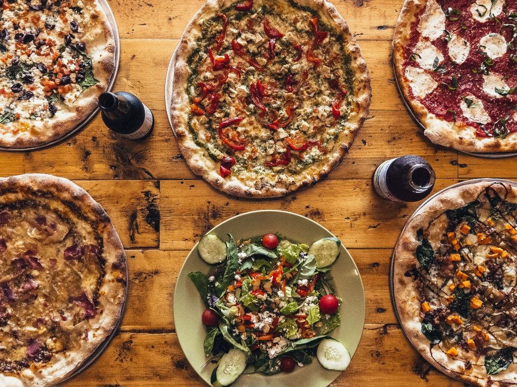 Stone L'Oven pizzas and salad on rustic wooden table